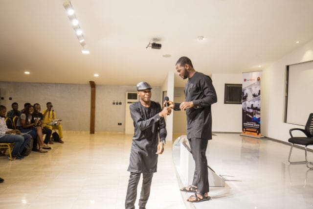 Codebeast and his friend, Prosper exchange mic at a conference they co-run